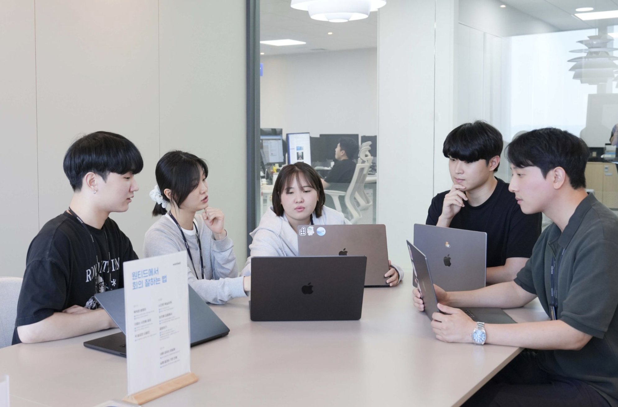 포지션 맵 프로젝트 팀이 회의 테이블에 모여 노트북으로 작업하는 모습