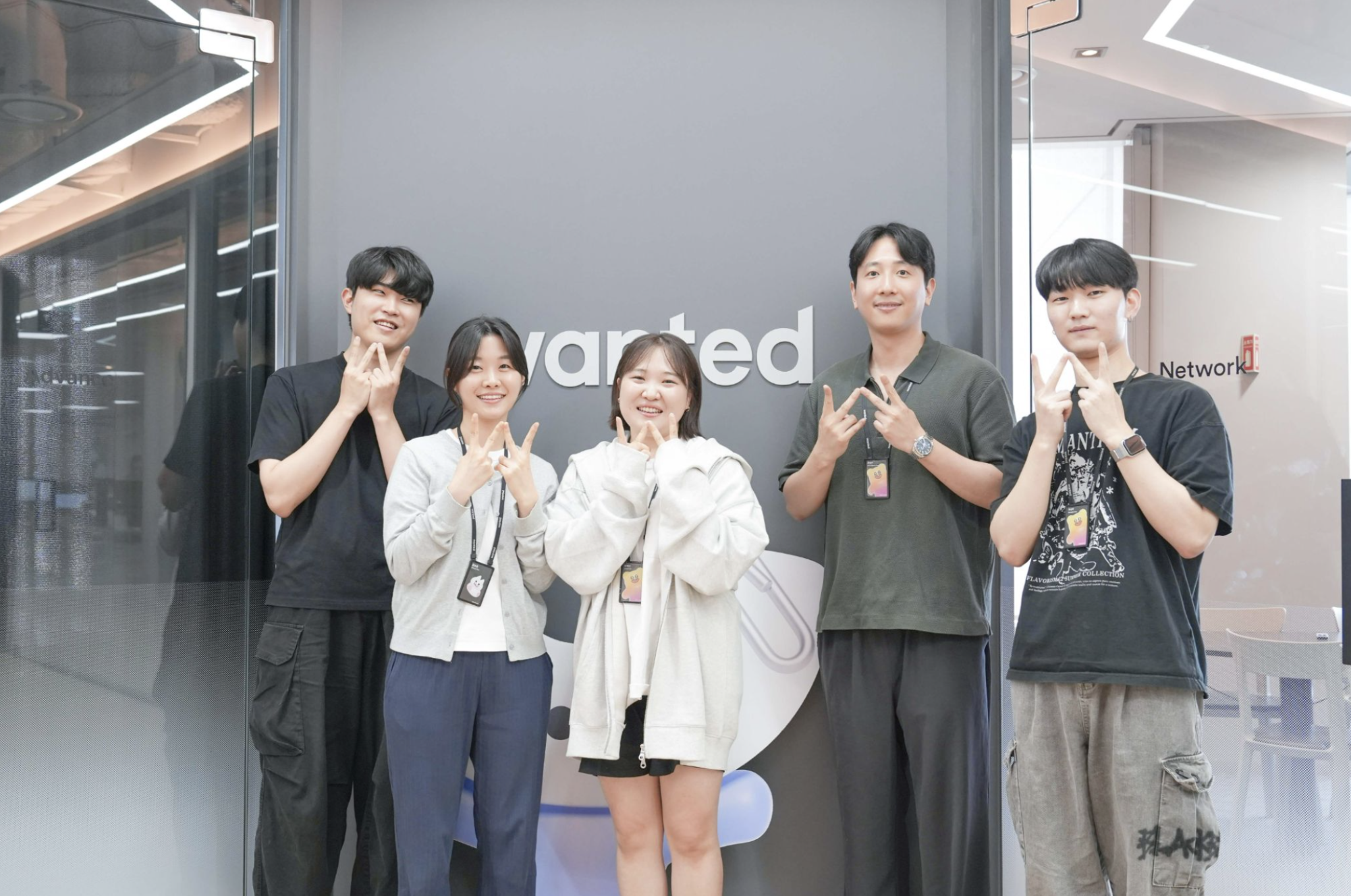 포지션 맵 팀이 원티드 사인 앞에서 손하트 포즈를 취한 모습