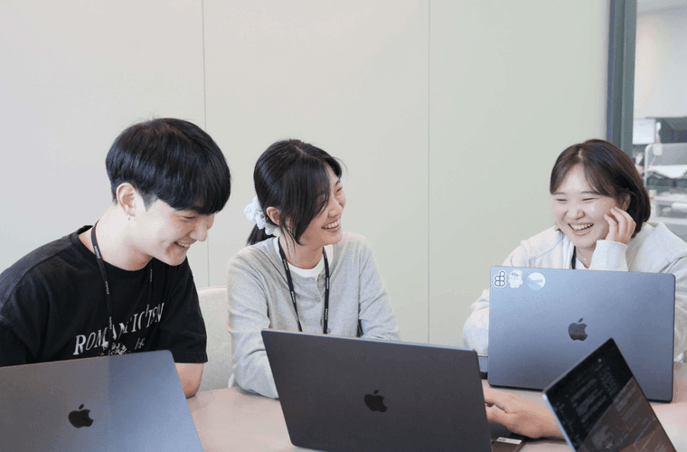 팀원들이 노트북을 보며 웃으며 이야기하는 모습